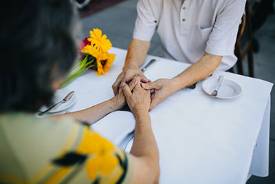 two family members holding hands at the dinner table